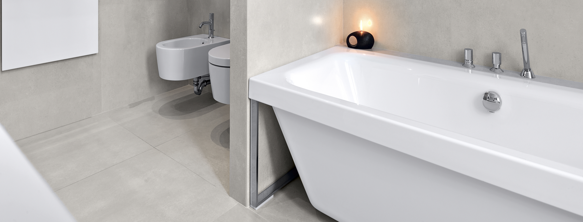 Modern bathroom with white tub, toilet, cabinet and black towel on towel rack.