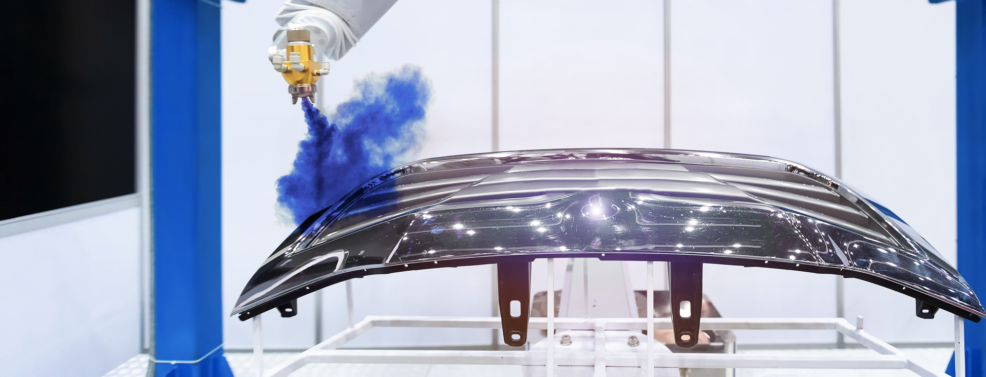industrial robotic arm paints a hood with blue paint