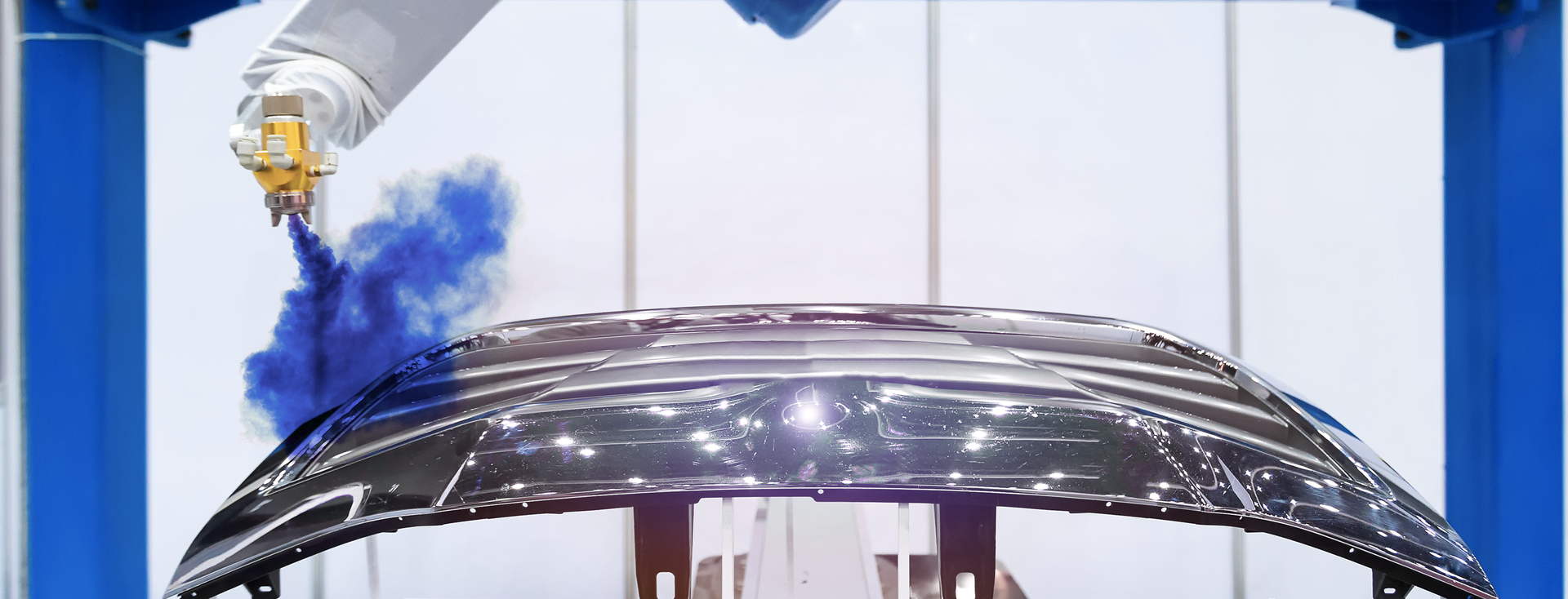 industrial robotic arm paints a hood with blue paint